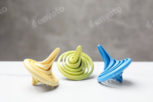 Preview: Bright spinning tops on white table, closeup