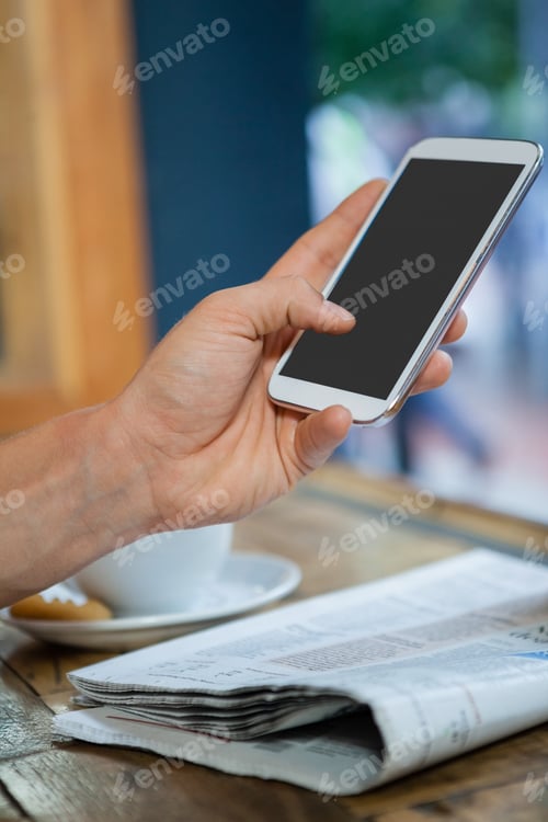 Preview: Cropped image of woman holding mobile phone at table