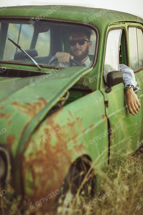 Preview: Young stylish handsome man, wearing shirt and sunglasses, drivin
