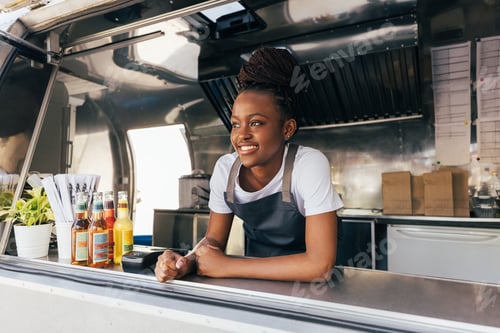 Preview: Smiling saleswoman in apron leaning counter standing in a food truck