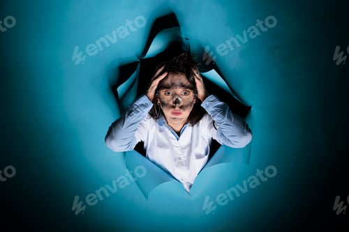 Preview: Worried crazy scientist with wacky appearance putting hands on head after failed chemical experiment