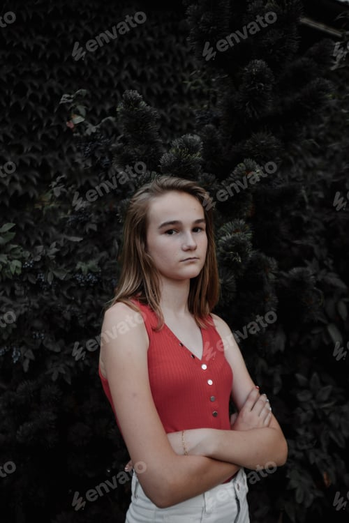 Preview: Teen Poses with Folded Arms Near Greenery