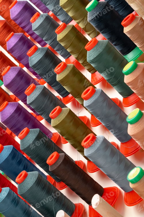 Preview: Row of multicolored thread spools at sewing factory
