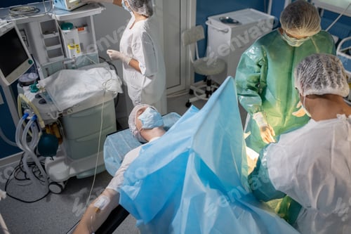 Preview: Patient lying on operation table while professional surgeons bending over him