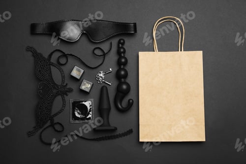 Preview: Shopping bag and different sex toys on black background, flat lay