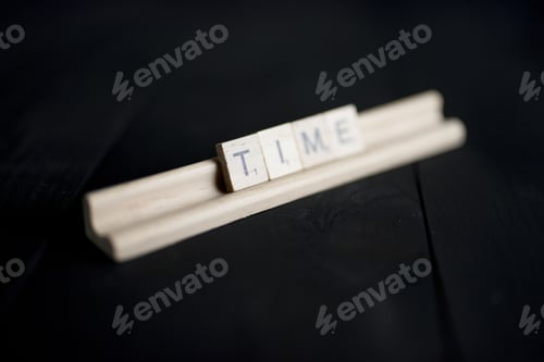 Preview: Closeup shot of wooden blocks spelling out time on a black wooden surface