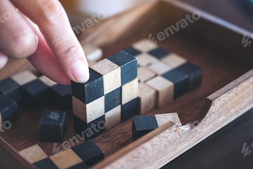 Preview: Closeup image of people playing and building wooden puzzle game