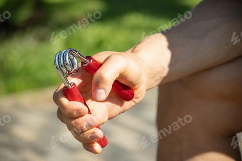 Preview: Sports red metal expander in man's hand.