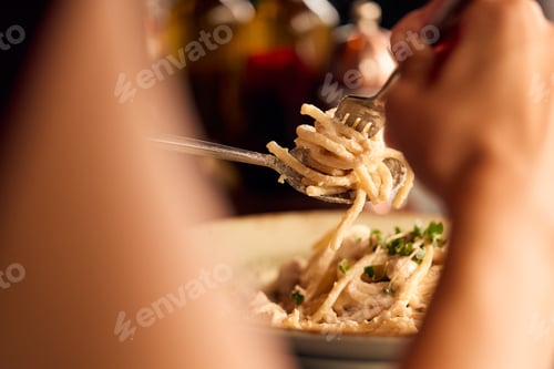 Preview: Close-Up of Hands Twisting Pasta Using Fork and Spoon at a Restaurant