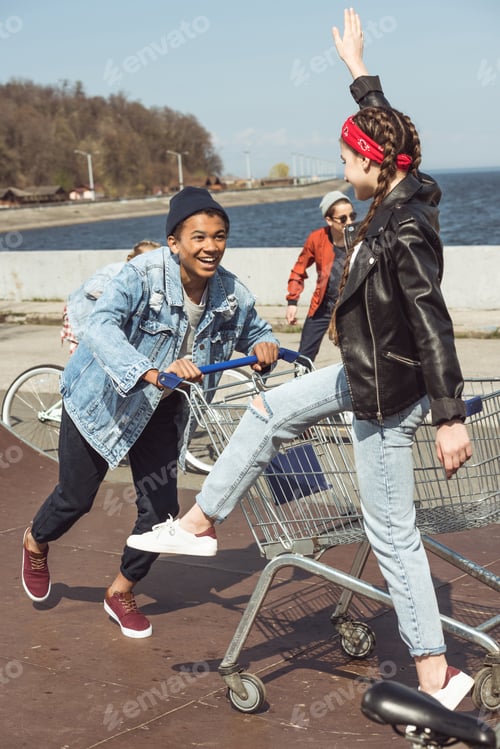Preview: teenagers having fun with shopping cart and bicycle in skateboard park