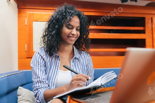 Preview: Ethnic female freelancer making notes