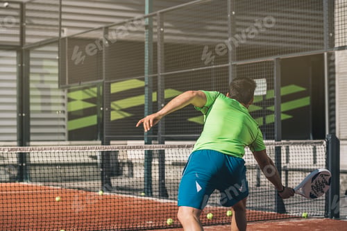 Man playing paddle tennis outdoors in bright sunlight