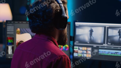 Preview: Post production studio employee working with raw footage while listening music in headphones