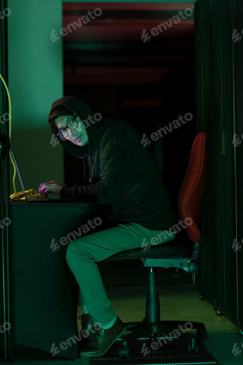 Preview: Asian male hacker using a laptop in computer server room
