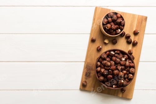 Preview: Wooden bowl full of hazelnuts on table background. Healthy eating concept. Super foods