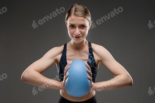 Preview: Sport caucasian girl with slim figure do exercises with blue ball isolated on black background