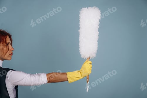 Preview: Big dust brush in hand of the professional maid. Woman is in the studio against background