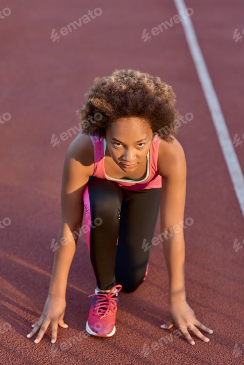 Preview: Sporty little girl standing in start position before the sprint
