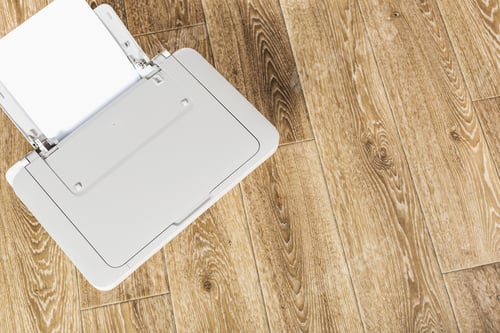 Preview: Printer on wooden floor with open tray ready for documents at home office workspace during daytime