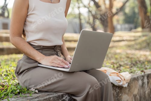 Preview: Sustainable lifestyle. Young woman working on her laptop in a park.