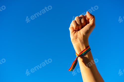 Preview: Hand of a woman with closed fist in favor of feminism, blue sky background