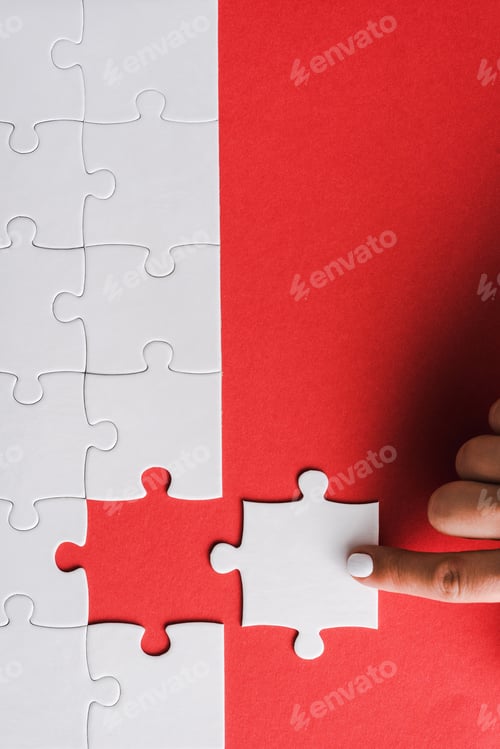 Preview: top view of woman pointing with finger at white jigsaw near connected puzzle pieces on red