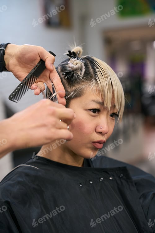 Preview: Hairdresser cutting hair of young female model in salon