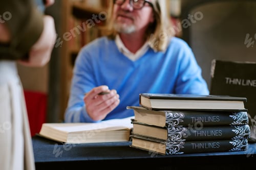 Preview: Middle Aged Caucasian Man Signing Books during Presentation Event Indoors
