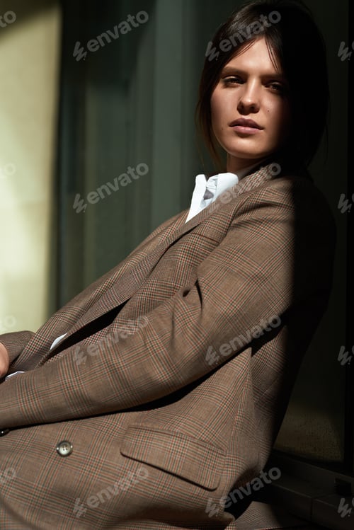 Preview: High fashion portrait of young elegant woman in brown suit walk on the street. enjoy summer lights.