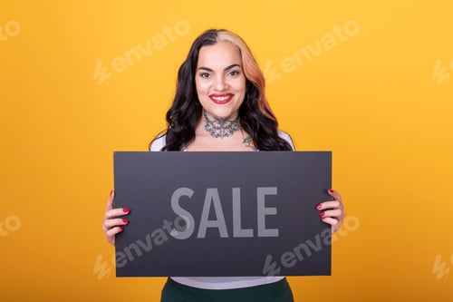 Preview: Beautiful woman holding a Sale sign against a yellow background