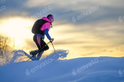 Preview: Woman Snowshoeing Across Snowy Field at Sunset