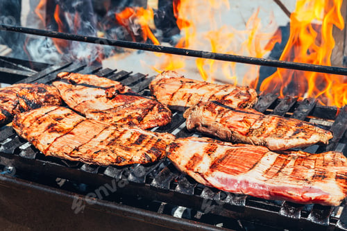Preview: barbecue steaks cooking on a flaming grill
