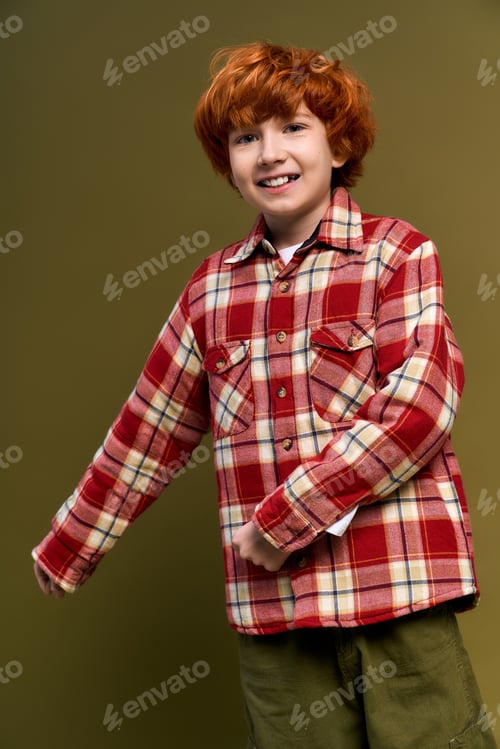 Preview: Little boy showcases charming fashion in stylish plaid shirt against a warm backdrop