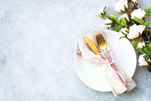 Preview: Table setting with white plate, cutlery and flowers.