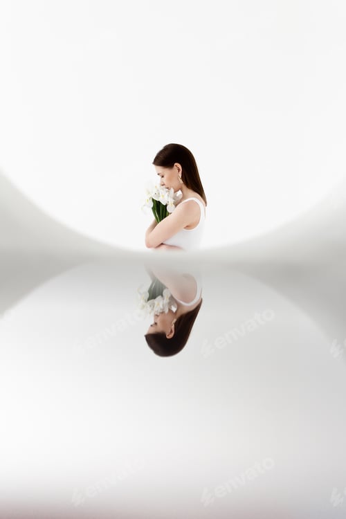 Preview: A young beautiful female woman holding flowers , wearing golden rings and white body, wearing jeans