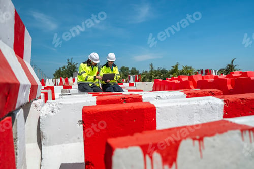 Preview: An engineer in visibility jacket and helmet working on construction site.