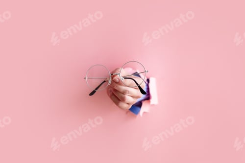 Preview: woman hand hold glasses on pink background.