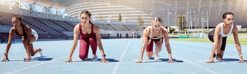Preview: Group of determined female athletes in starting position to begin a sprint or running race on a spo