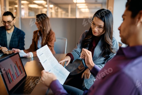 Preview: Asian businesswoman going through reports with colleague during meeting in the office.