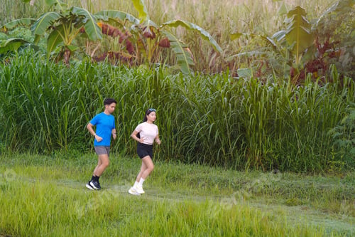 Preview: Asian Couple Jogging Together on Trail Through Lush Green Countryside
