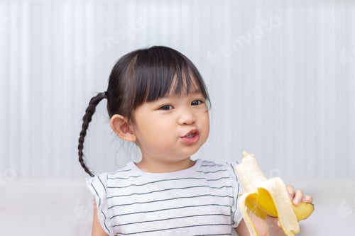 Preview: Child Enjoying Fresh Banana Snack Indoors