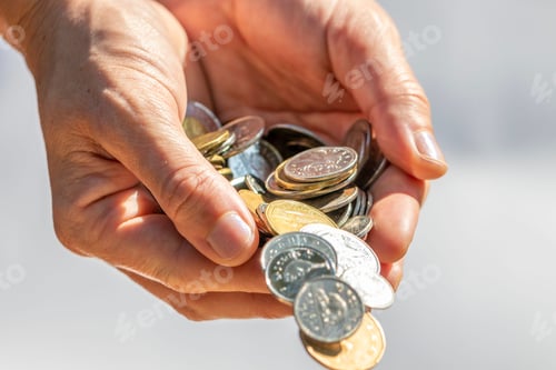 Preview: Closeup shot of two hands full of Canadian cash coins and dropping them