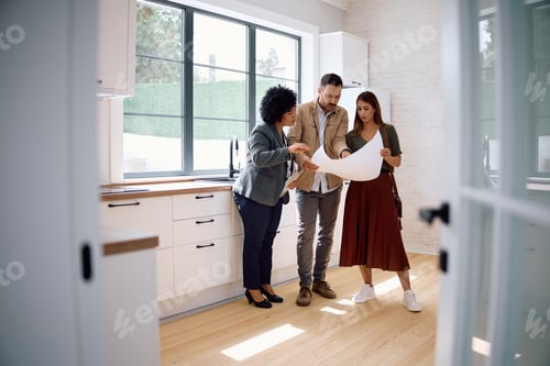 Preview: Real estate agent and a couple analyzing blueprints in the kitchen of a new house. .