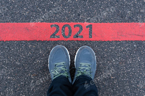 Preview: top View of male sneakers on the asphalt road with text 2021 on red line, new year concept