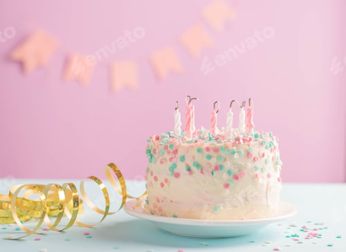 Visualização: Bolo festivo com velas apagadas contra fundo de bandeiras de parede rosa festivas em serpentina