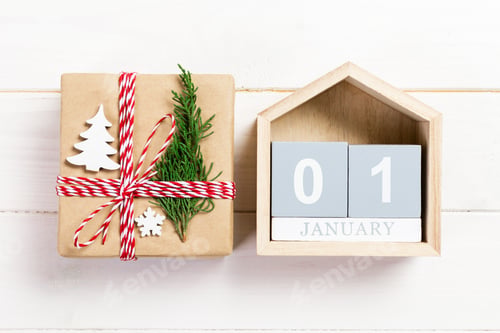 Preview: Christmas calendar 1 january. Christmas gift, fir branches on wooden white background