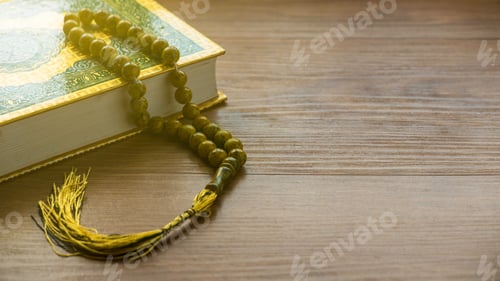 Preview: Selective focus of rosary beads and Quran on a wooden background with copy space.