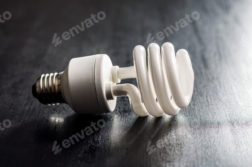Preview: Energy saving light bulb on black table. Fluorescent Lightbulb