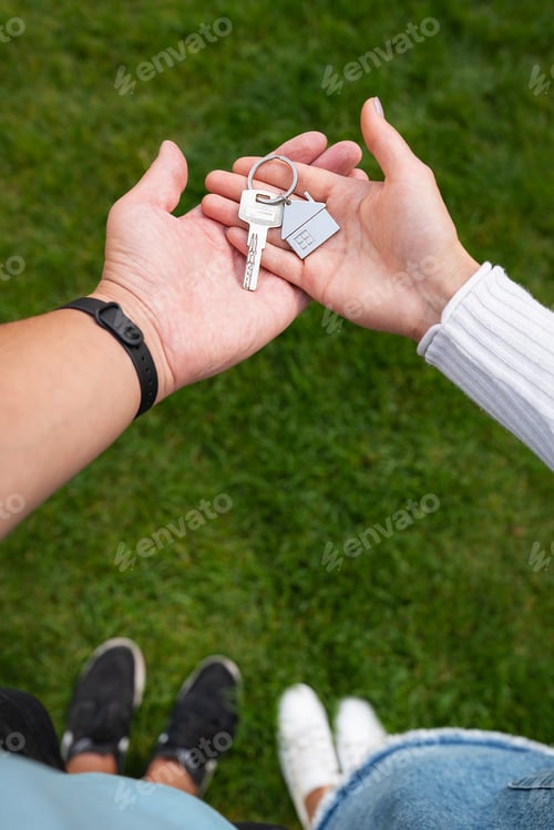 Preview: Keys with a keychain in the form of a metal house from a new house or apartment in the hands