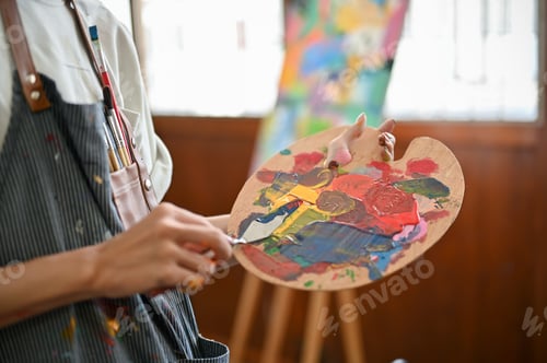 Preview: Close-up image of a professional male artist mixing colors on a palette